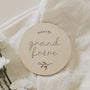 Disque en bois rond gravé « bientôt grand frère » sur tissu beige avec fleurs blanches