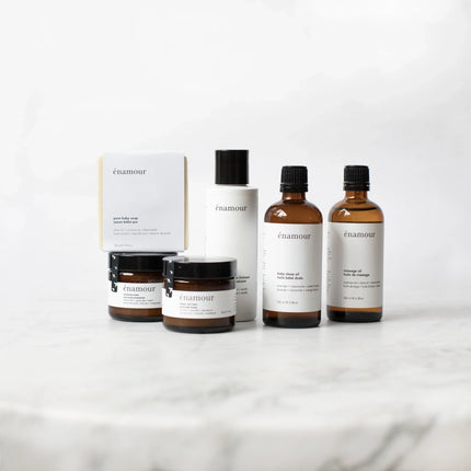 Gamme de produits soin bébé énAmour incluant savon, baumes et huiles sur surface marbrée blanche