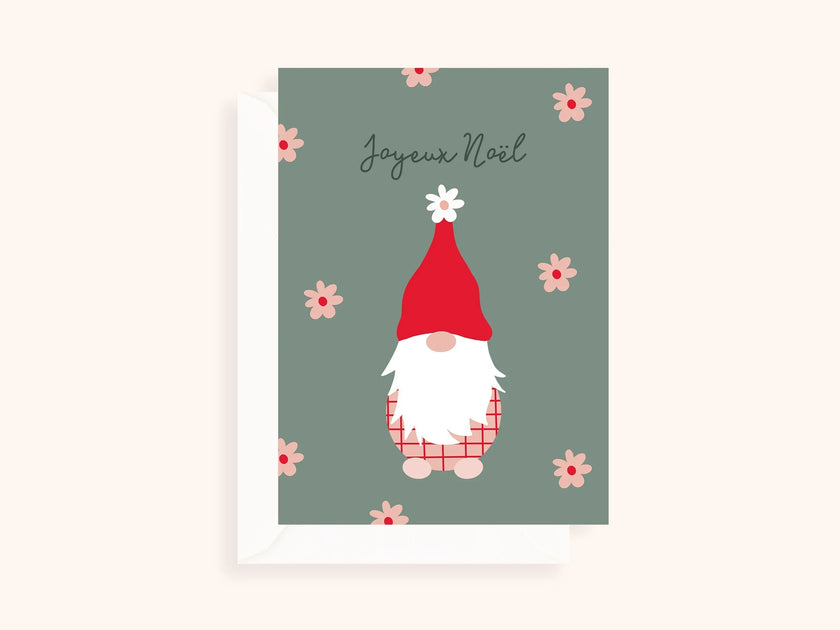 Carte de Noël avec un lutin au bonnet rouge, fond vert et fleurs roses, texte Joyeux Noël