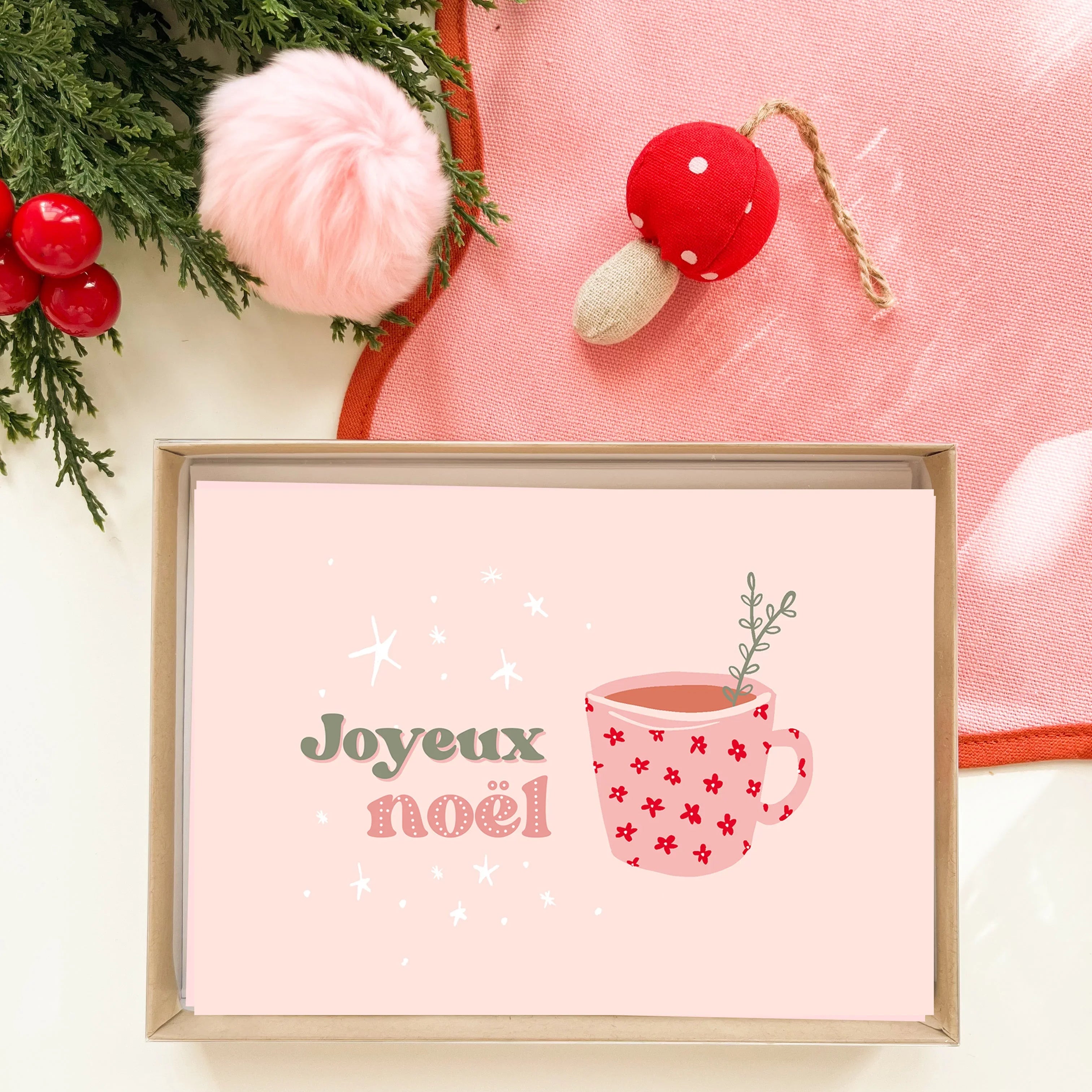 Coffret carte de Noël rose avec message joyeux noël et tasse de café décorée, branches de sapin et décorations