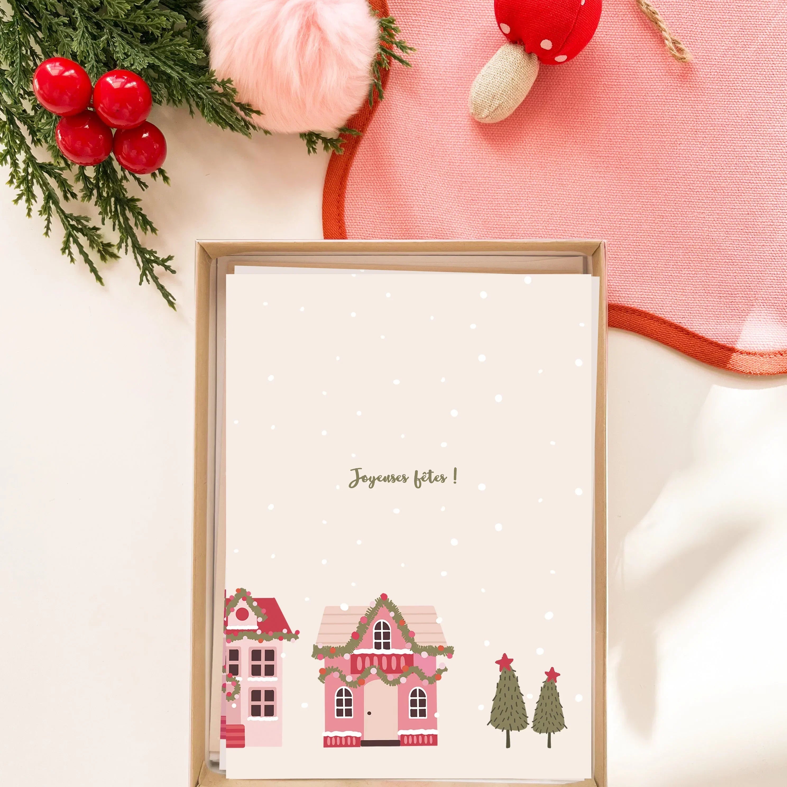 Carte de vœux de Noël avec village décoré et texte Joyeuses fêtes, décorations rouges et vertes