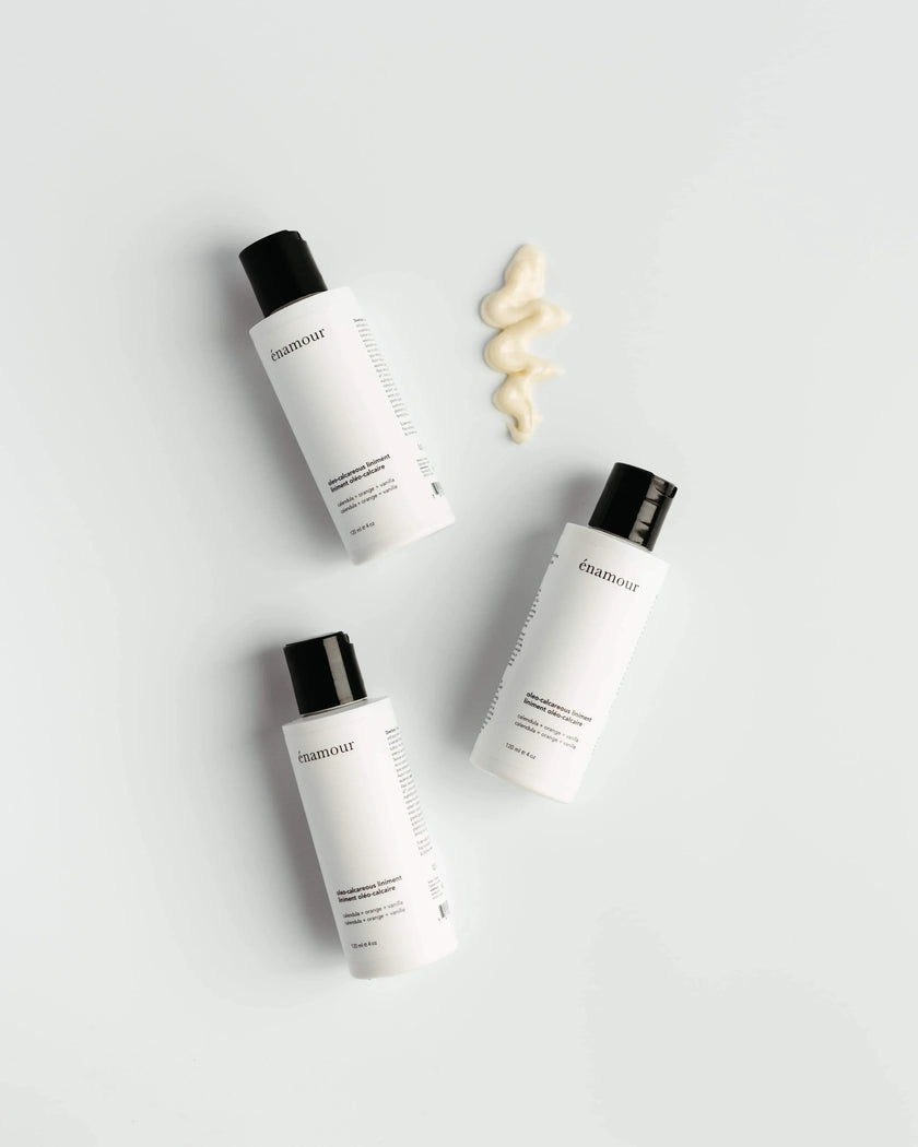 Trois bouteilles blanches de liniment oléo-calcaire énamour avec un échantillon de crème beige sur fond blanc