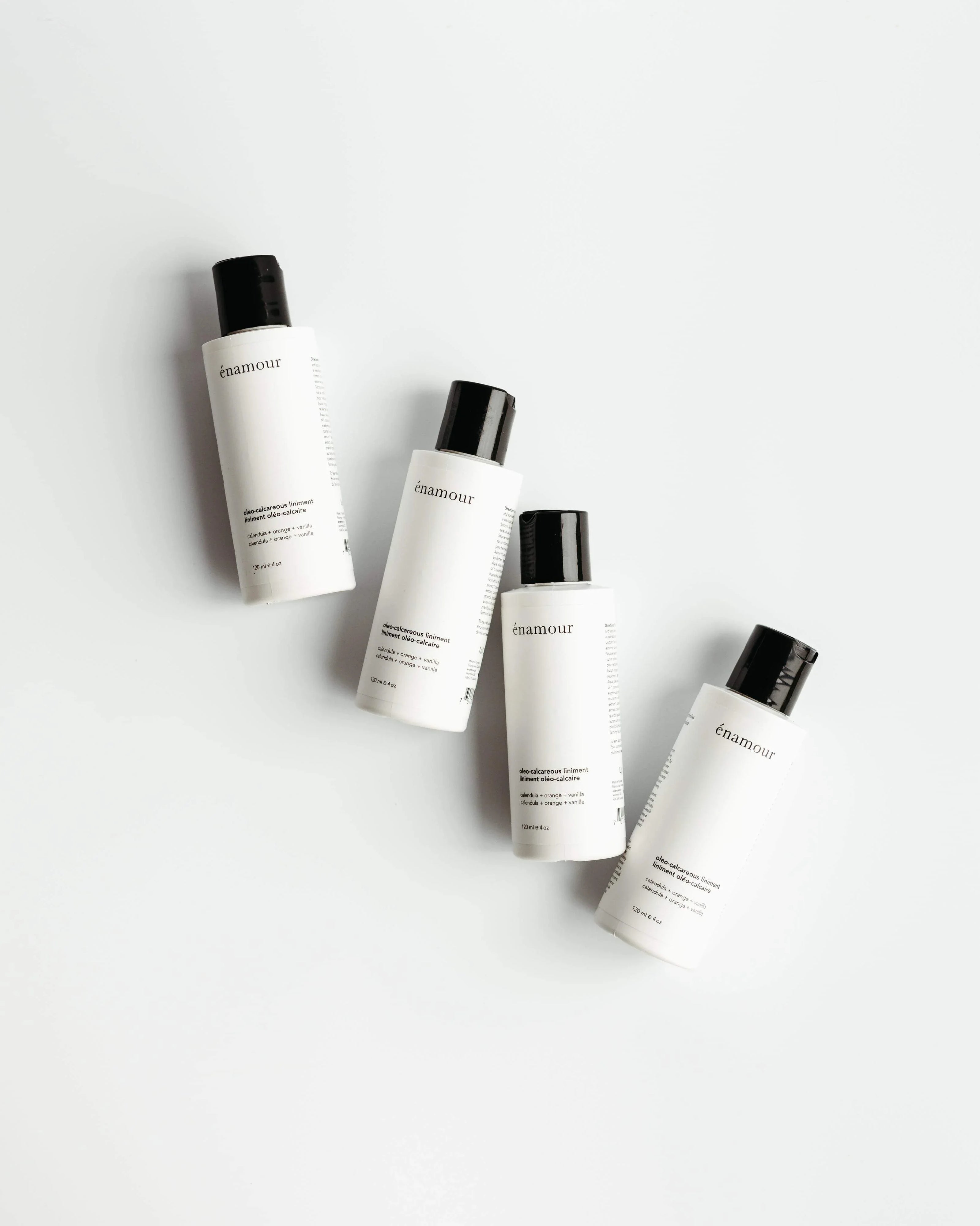 Quatre flacons de liniment oléo-calcaire én amour, calendula, orange, vanille sur fond blanc