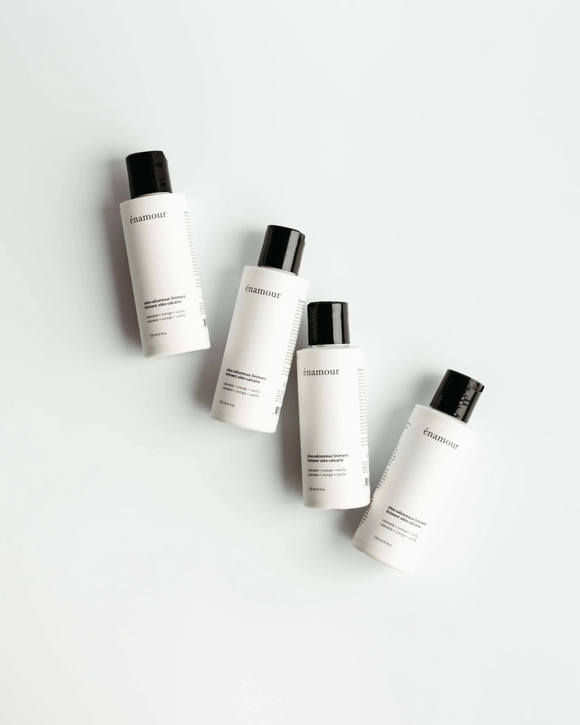 Quatre flacons de liniment oléo-calcaire én amour, calendula, orange, vanille sur fond blanc