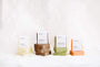 Quatre piles de savons naturels énamour aux couleurs crème, marron, vert et orange sur fond blanc