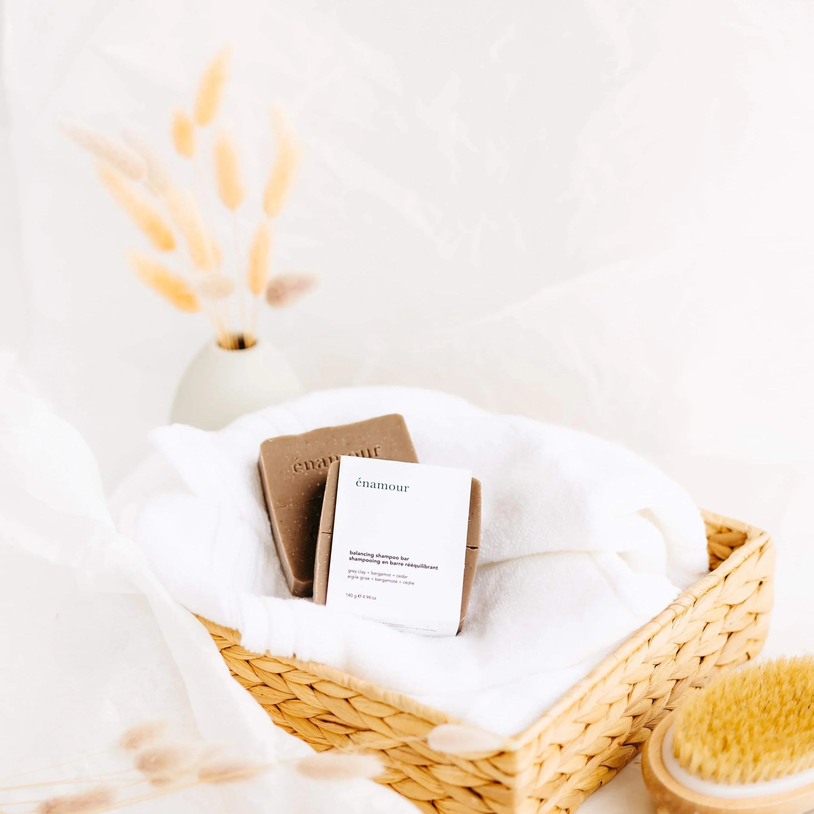 Panier en osier avec serviette blanche et shampooing solide énamour, décor minimaliste naturel