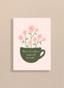 Carte avec tasse verte et fleurs roses, texte Merci à la meilleure enseignante du monde