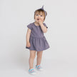 Bébé fille debout en robe vintage prune et bandeau assorti, chaussures colorées